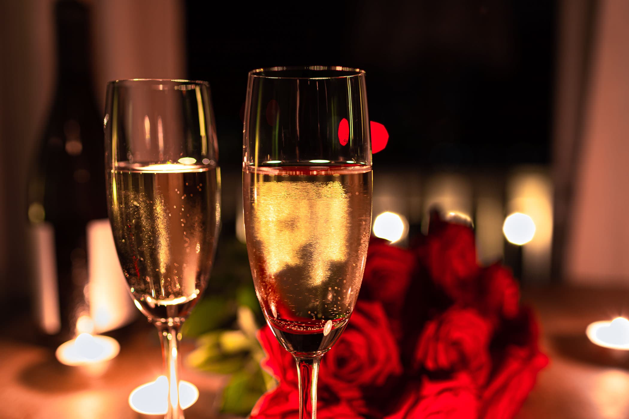 Closeup Of Champagne Glasses On Table With Red Roses And Candle