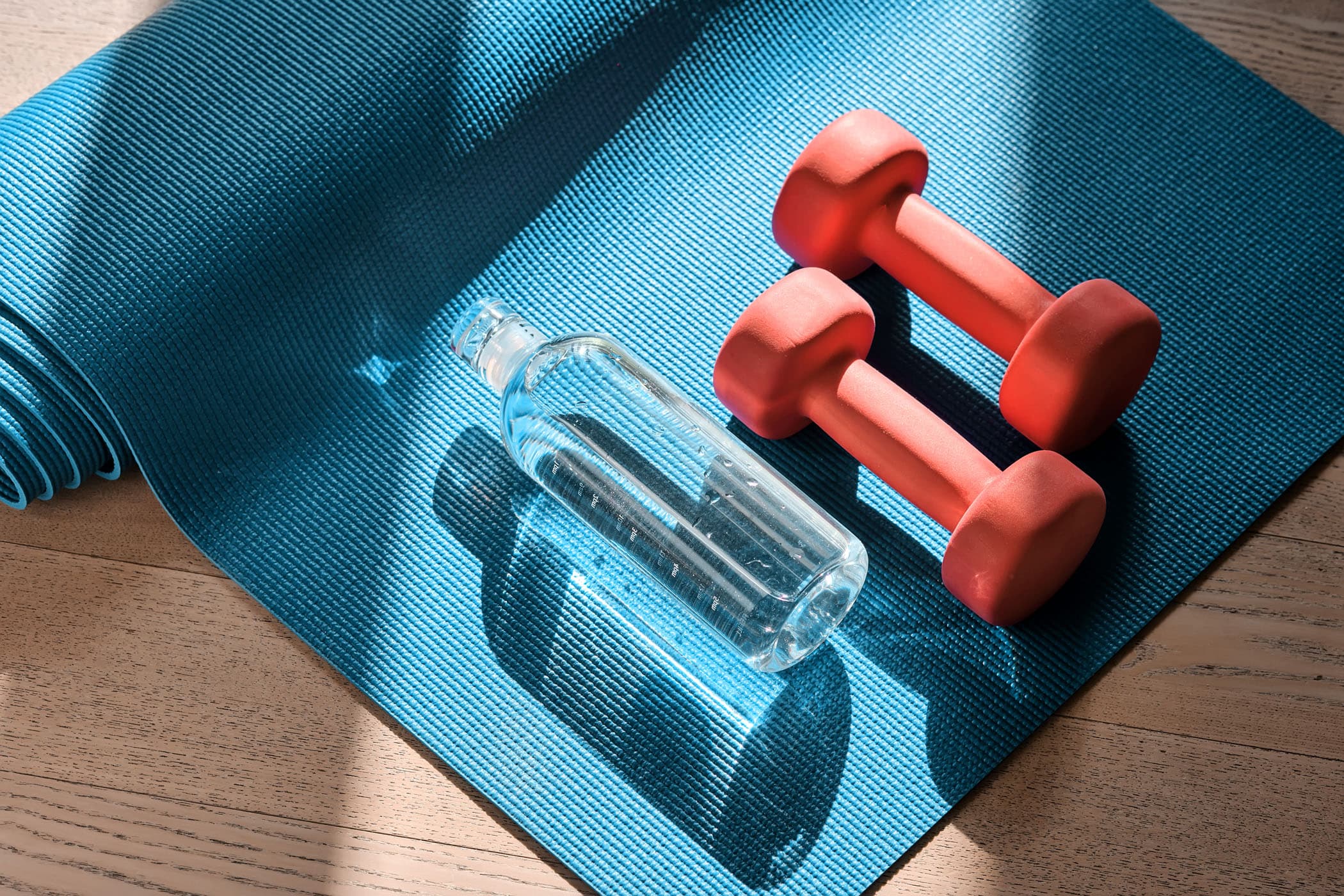 A yoga mat, hand weights and a bottle of water