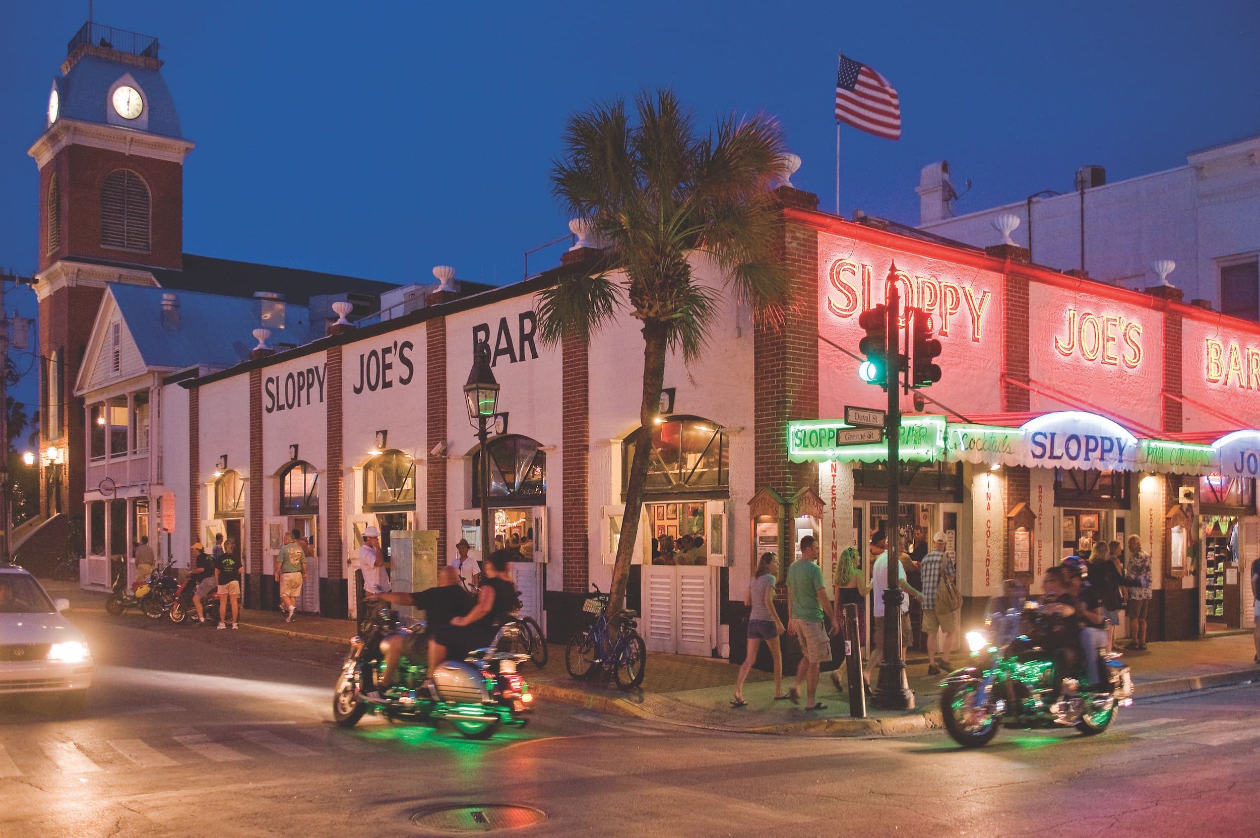 Exterior of Sloppy Joes Bar at night with a lot of foot traffic