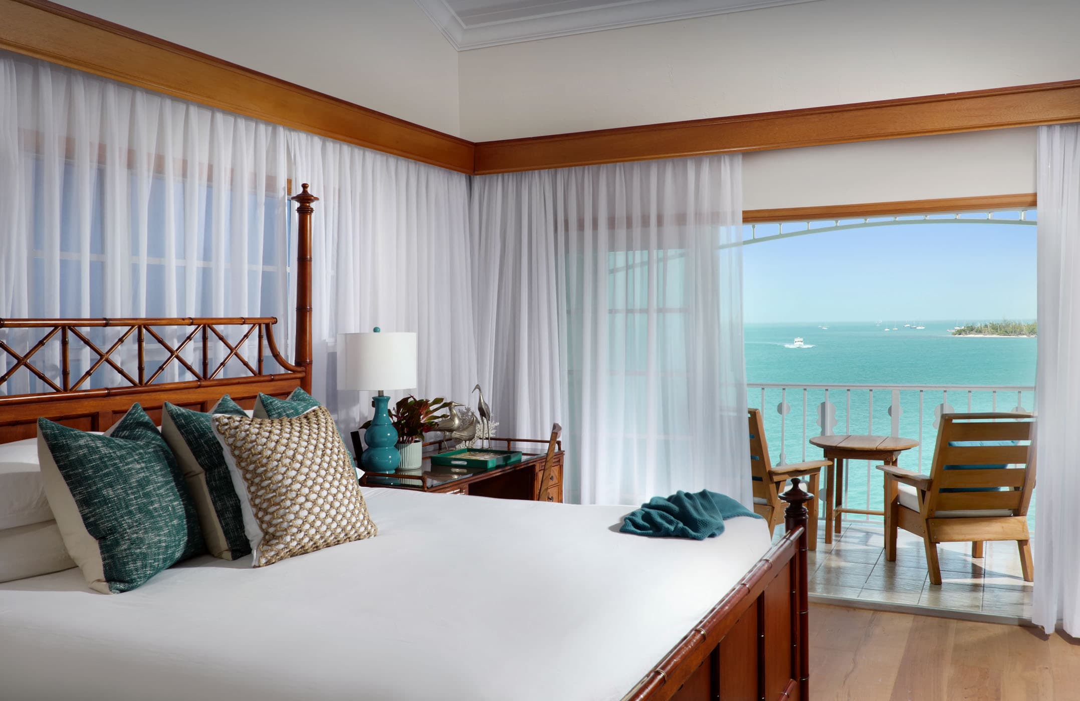 A king bed with a double door access to a balcony overlooking the water