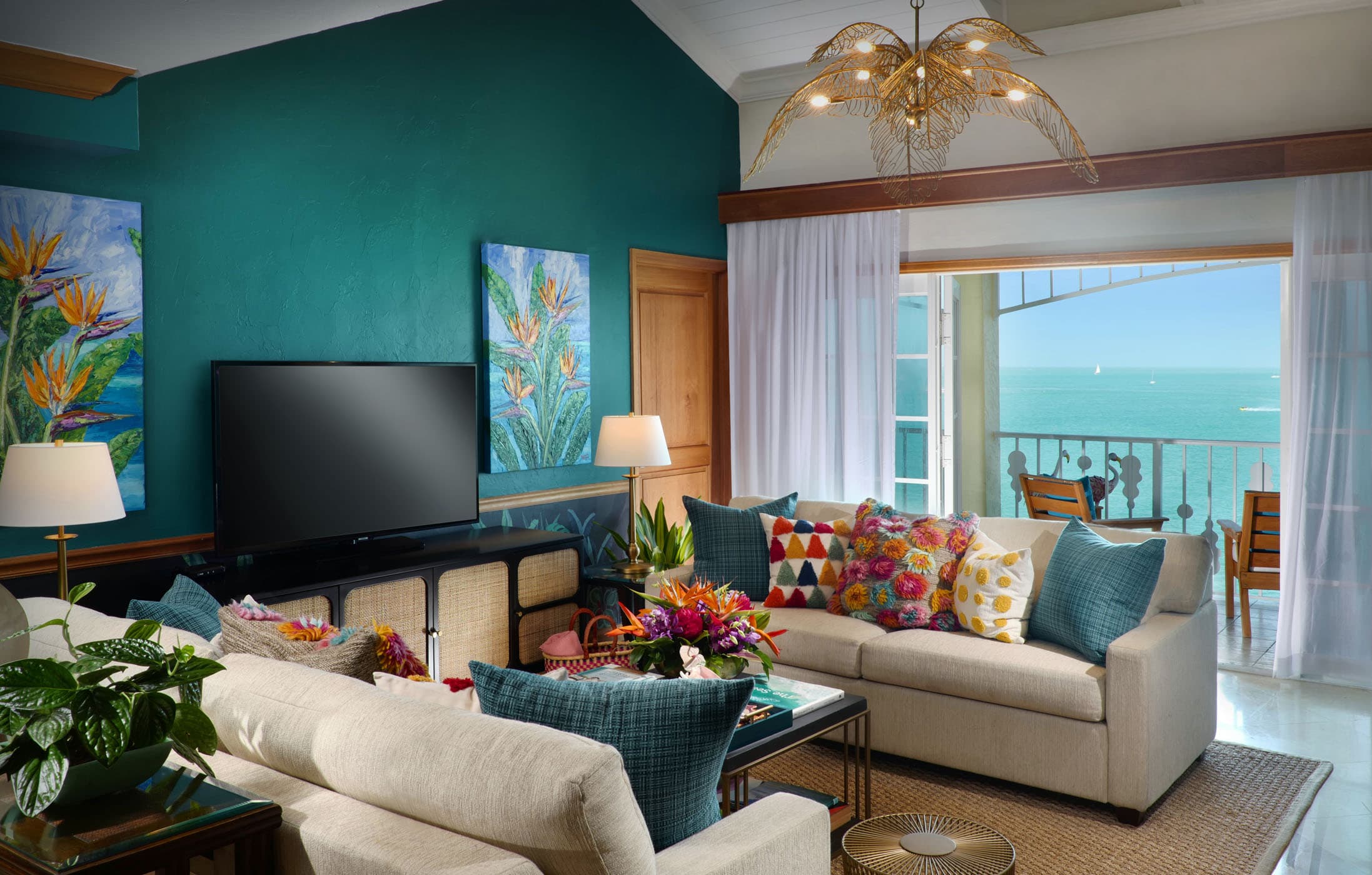 The living room with a large TV and access to a balcony overlooking the water at Ocean Key Resort