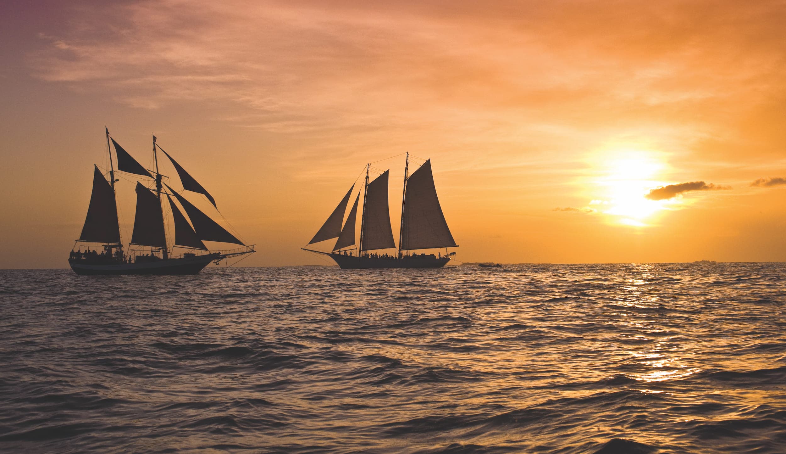 2 large sailboats on the water during a gorgeous sunset