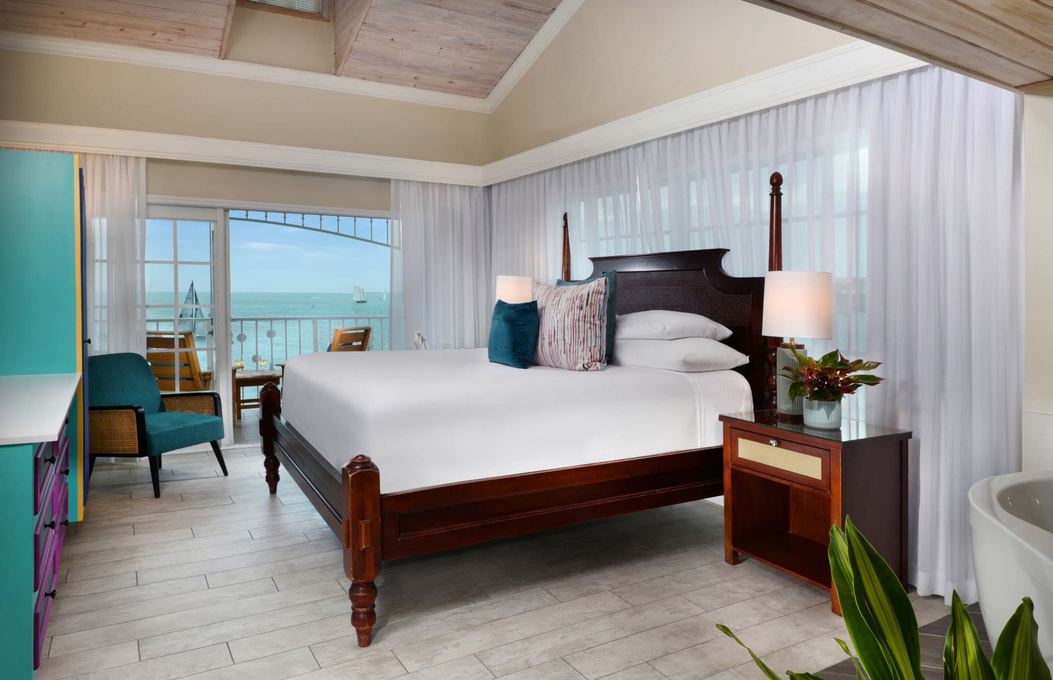 A queen bed in a 2 bedroom suite with access to a balcony overlooking water at Ocean Key