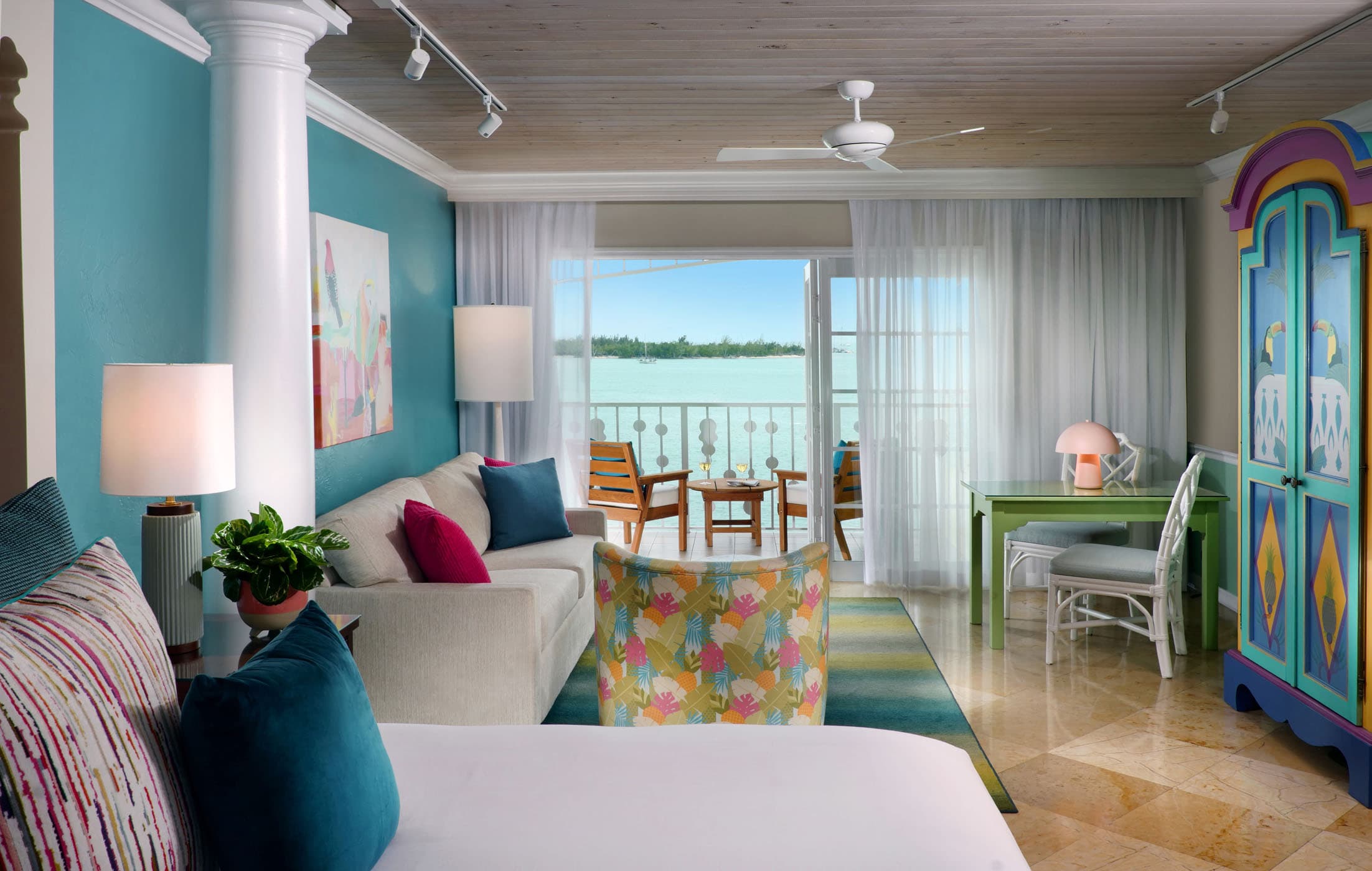 The Boutique Suite with a large bed, living space, and a balcony overlooking the water at Ocean Key