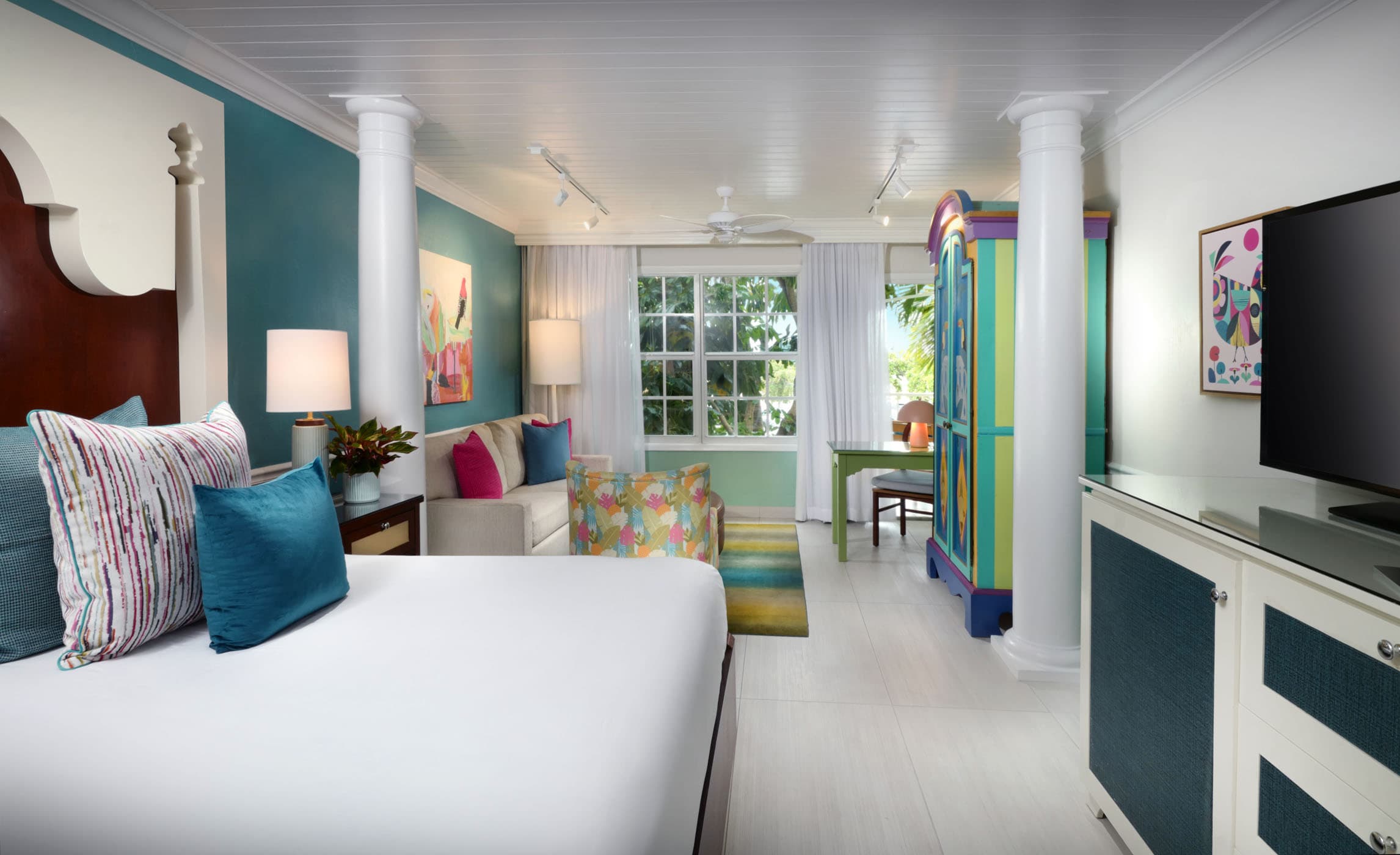 A standard guest room at Ocean Key with a living space, large bed and Tv