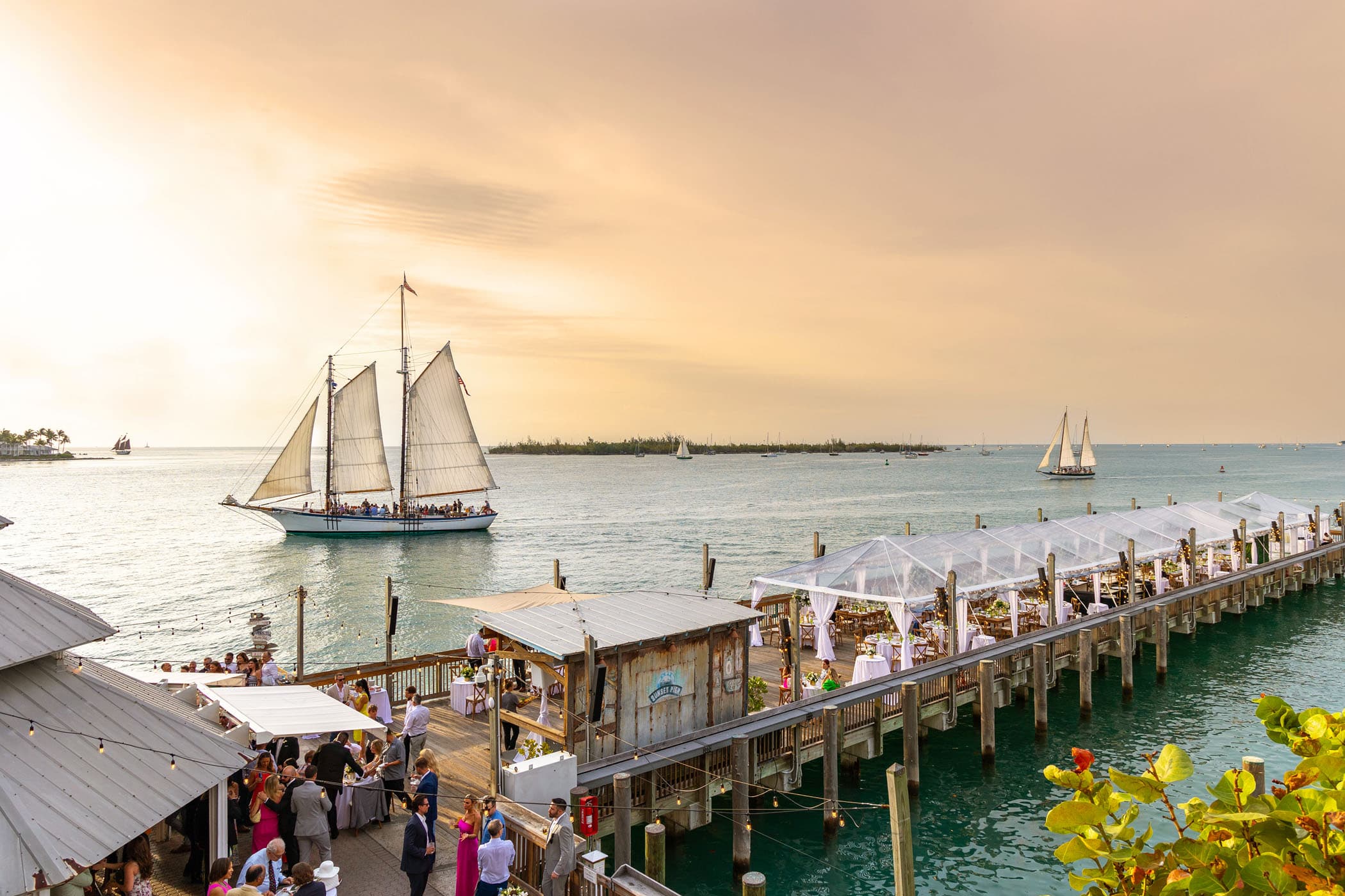 A sunset wedding on the pier at Ocean Key with 2 large sailboats in the water
