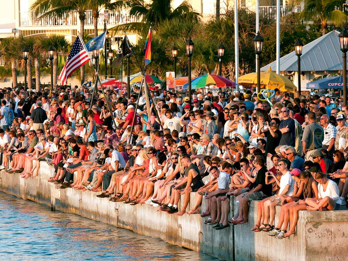 A crowd nat Mallory Square watching an event in the water at sunset