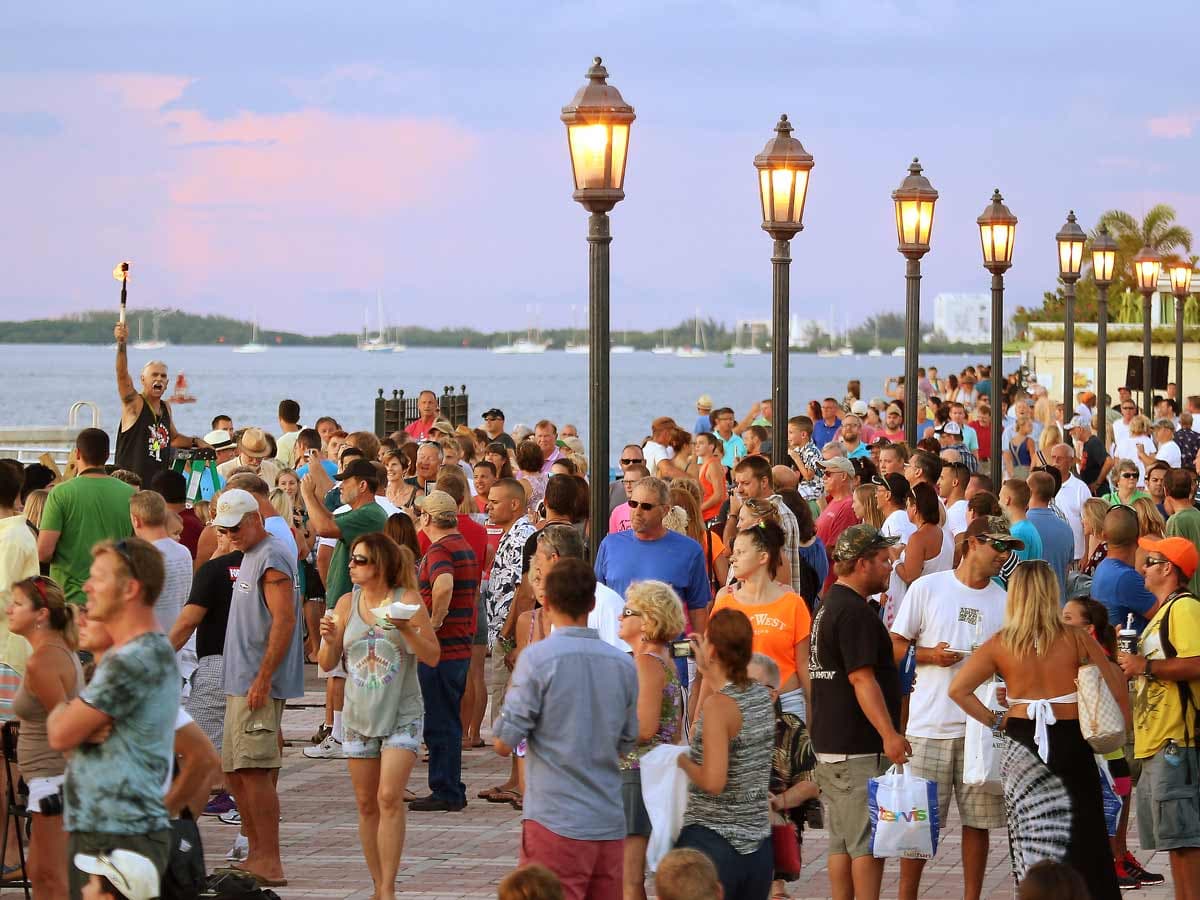 A large group of people walking down the boardwalk at mallory Square