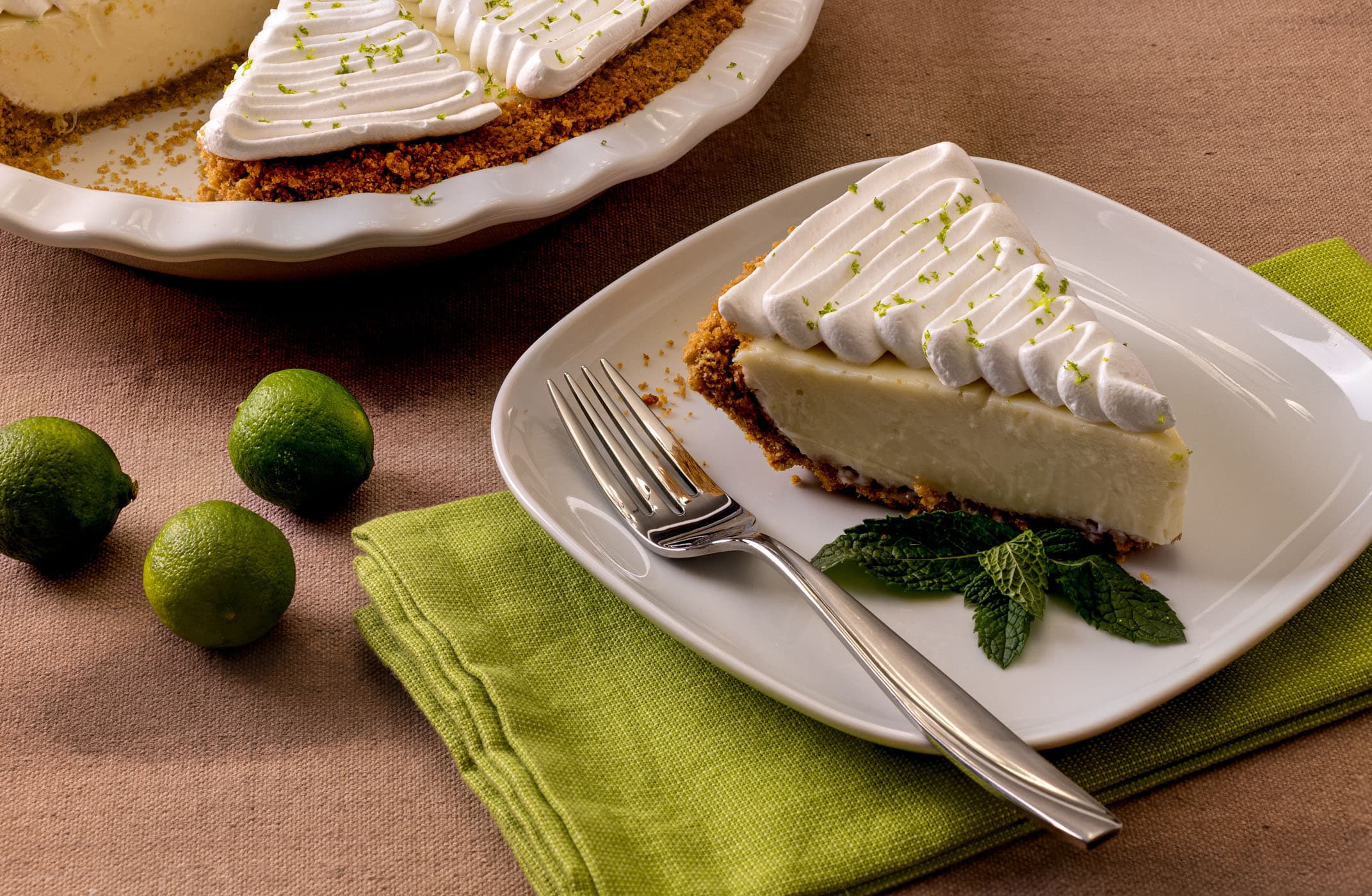 Close Up Of Lime Pie And Slice On Plate With Meringue And Mint