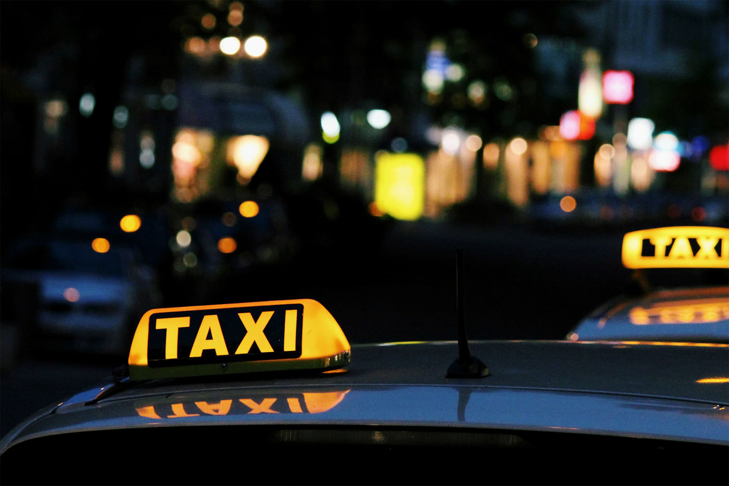 2 taxi signs on the top of taxis cabs