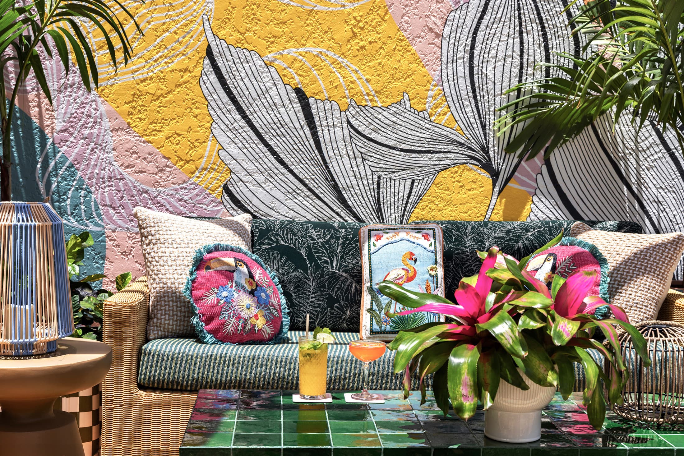 Colorful tropical mural wall art behind a dining table with floral centerpiece and lush indoor plants at Ocean Key Resort restaurant, Key West