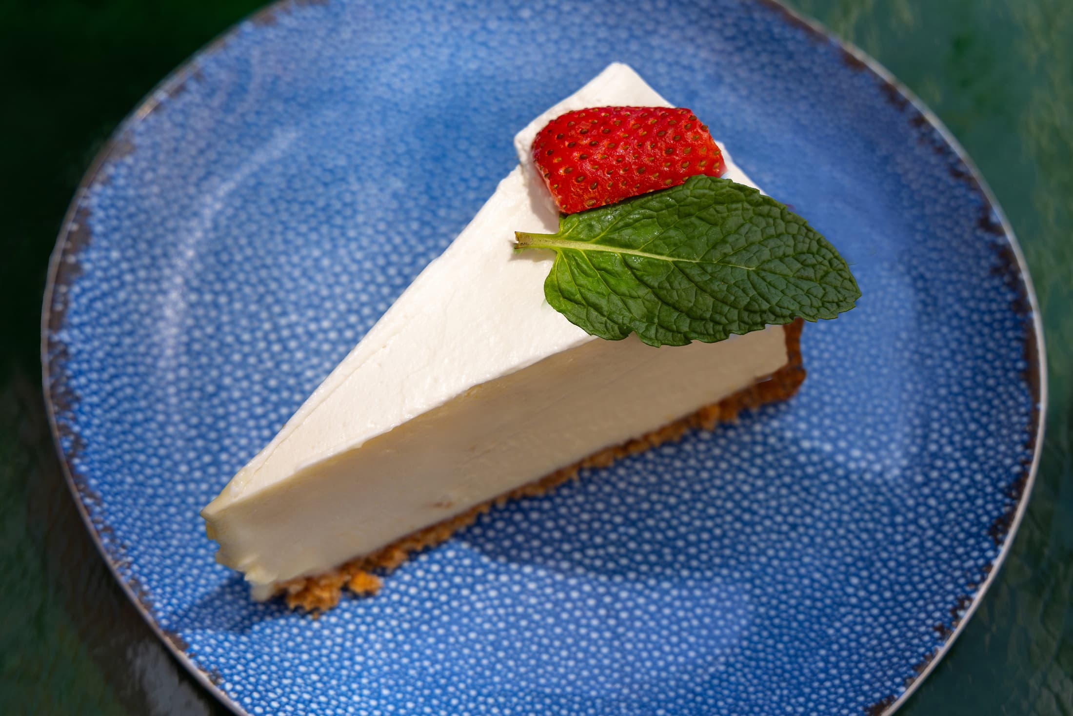 Slice of classic Key lime pie topped with whipped cream, mint leaf, and a fresh strawberry on a blue plate, signature dessert at Ocean Key Resort Key West