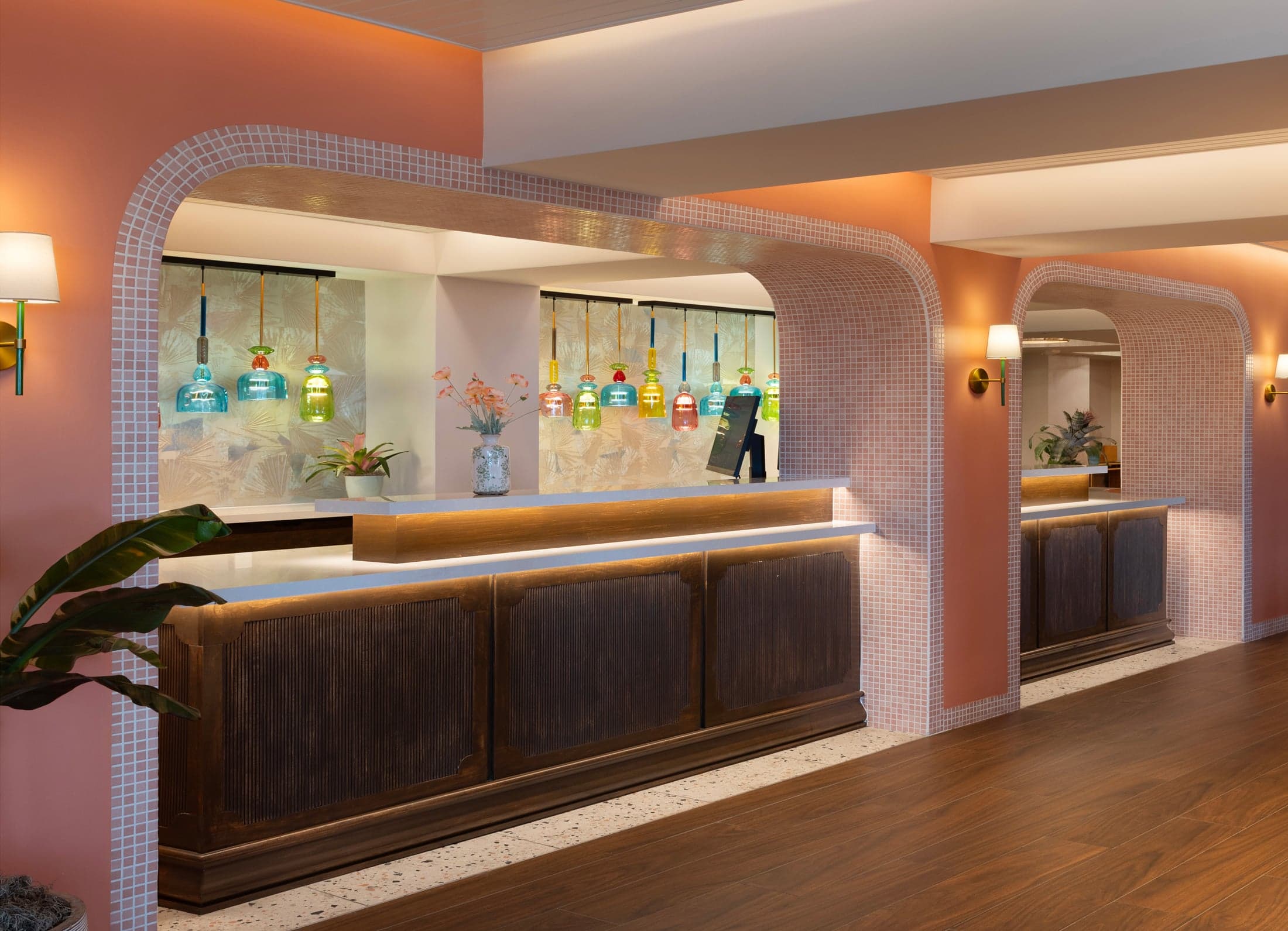 Hotel reception counter beneath a pink coral archway with framed artwork and warm ambient lighting at Ocean Key Resort, Key West