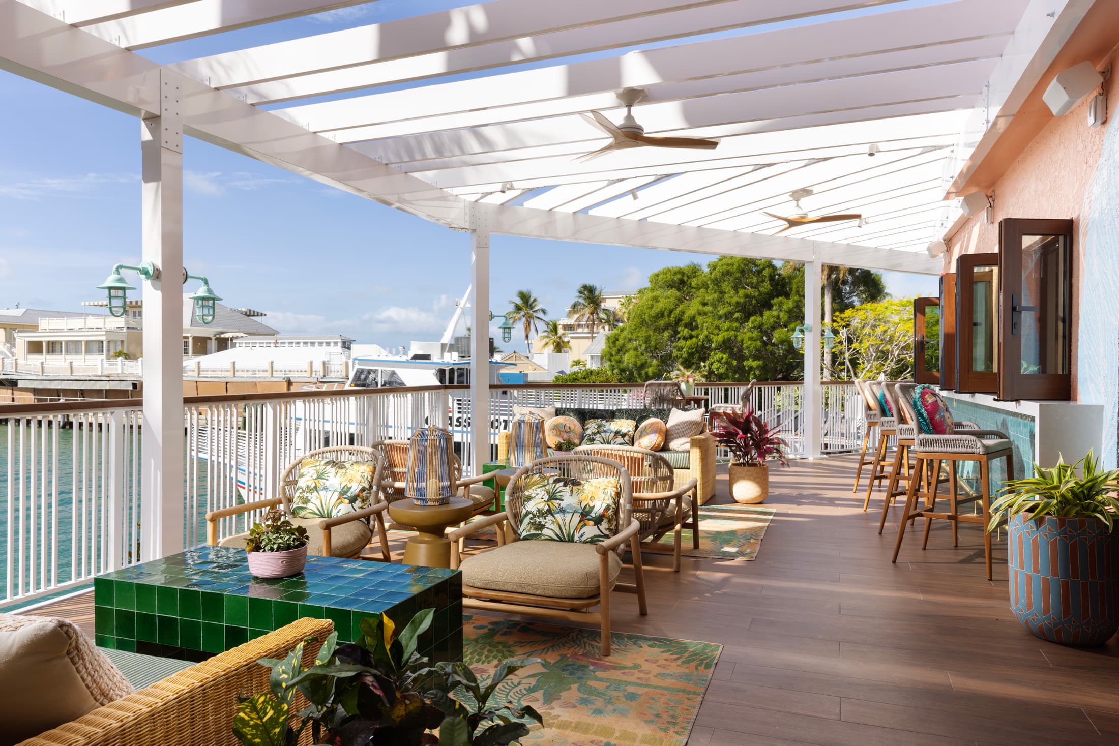 Open-air patio of Sweet Bird Bar with lounge seating, striped overhead canopy, and panoramic marina and ocean view at Ocean Key Resort, Key West
