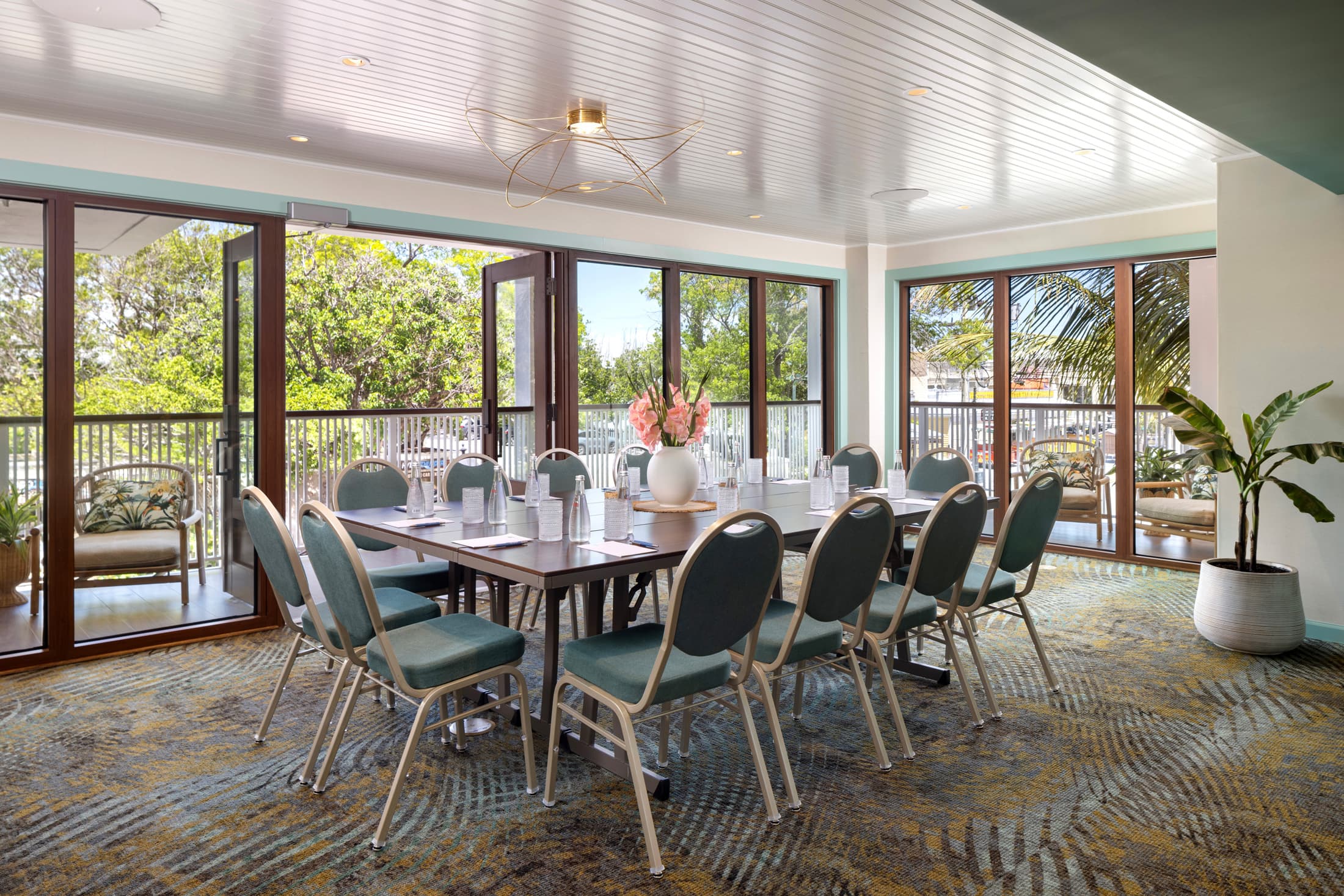 Private event or meeting room with long conference table, upholstered grey chairs, and floor-to-ceiling windows at Ocean Key Resort, Key West