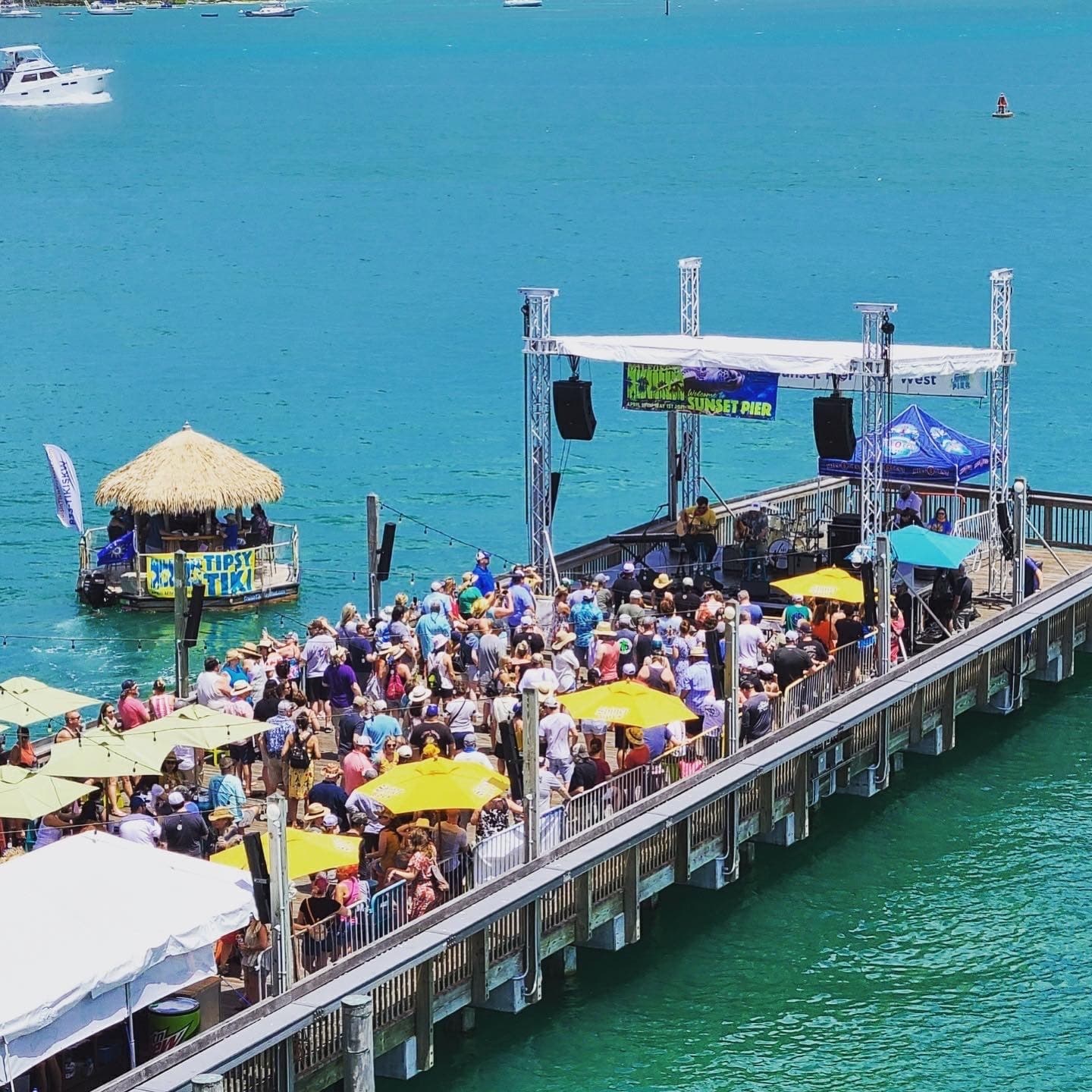 Festival crowd and tiki boats along Sunset Pier at Ocean Key Resort overlooking Key West, Florida waters
