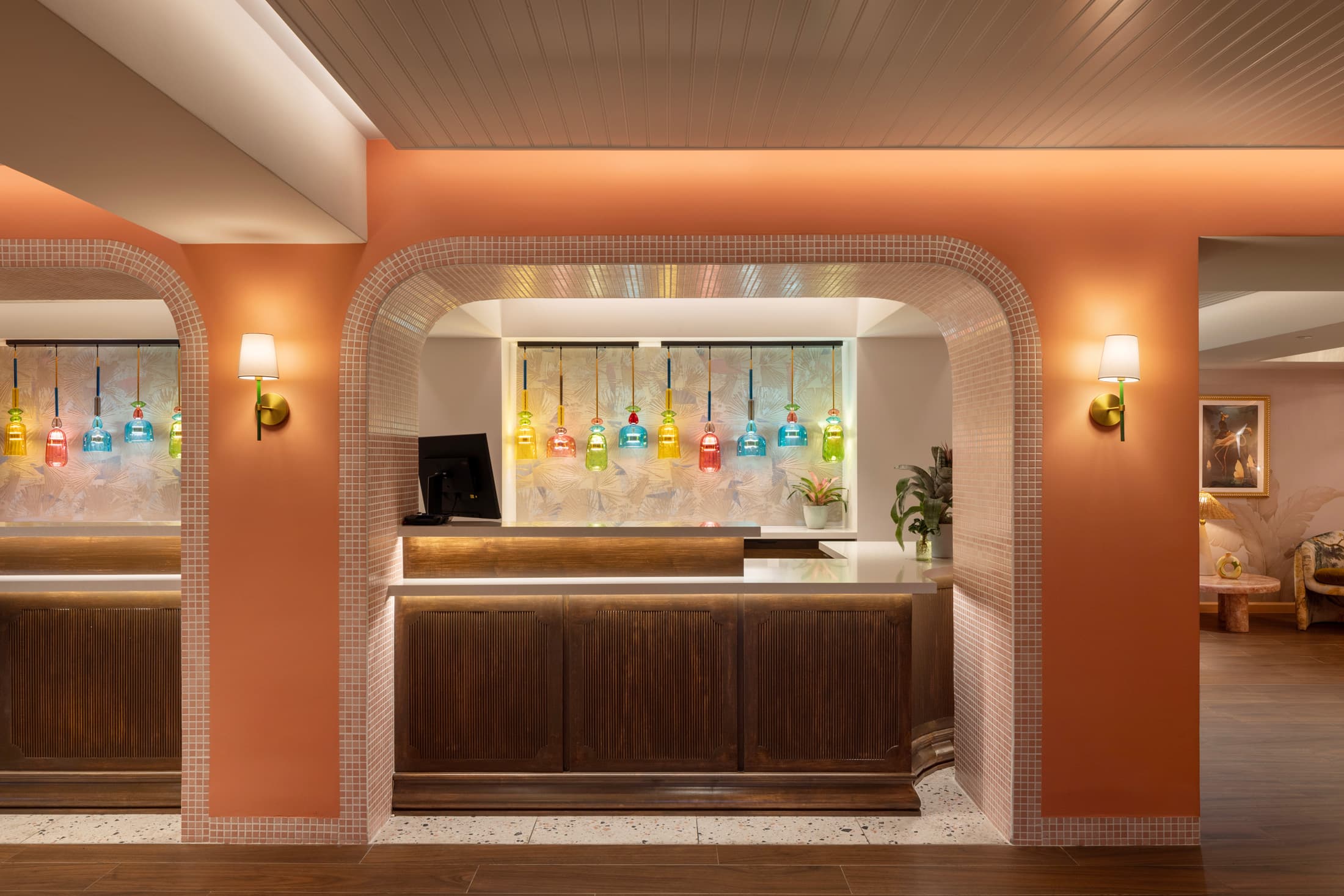 Front-facing check-in counter and host stand framed by coral walls and vibrant tropical artwork at Ocean Key Resort, Key West.