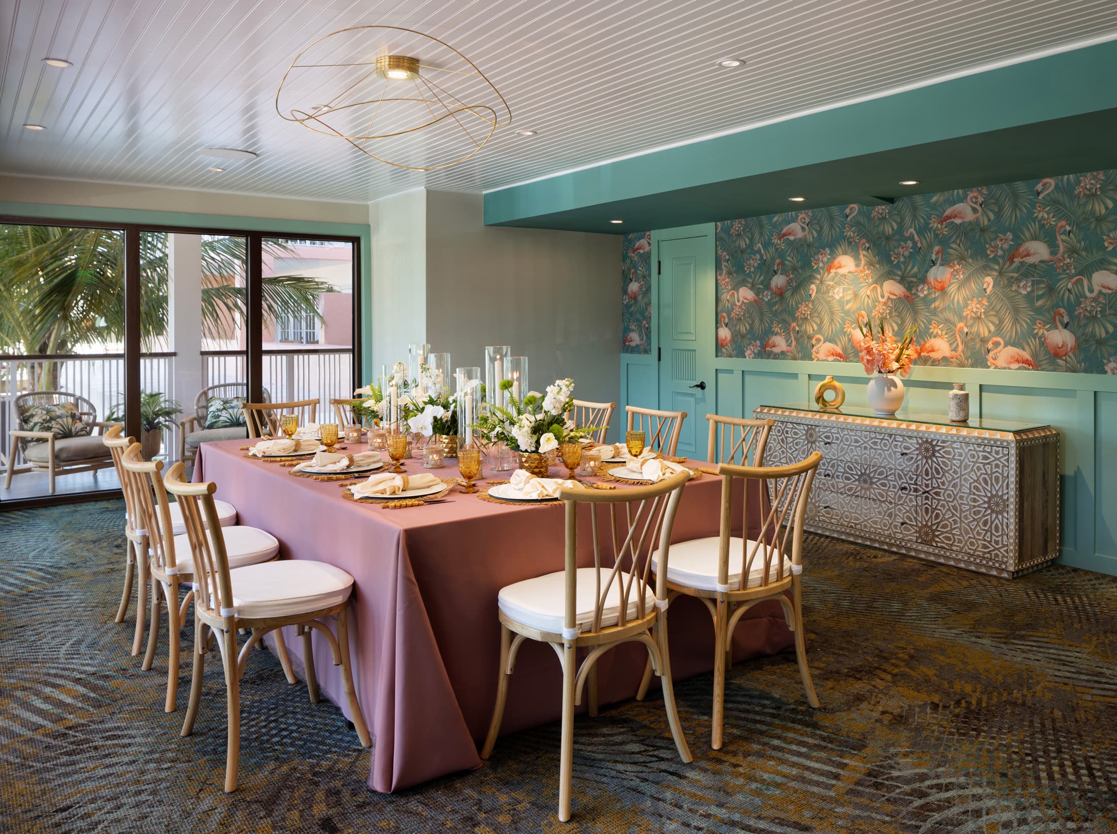 Private indoor dining room with pink tablecloths, vibrant tropical mural, and floor-to-ceiling windows at Ocean Key Resort, Key West