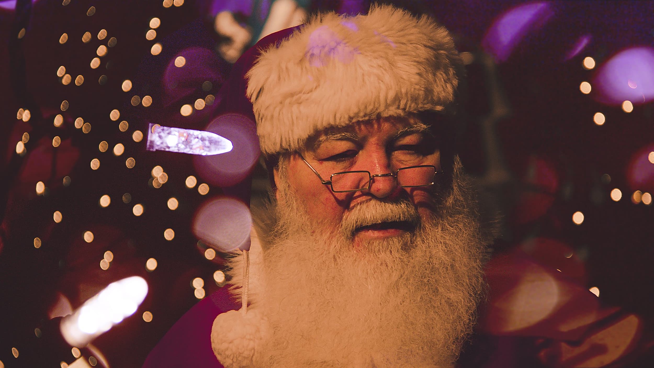 Santa Claus in glasses and a fur-trimmed hat among twinkling holiday lights at Ocean Key Resort in Key West, Florida